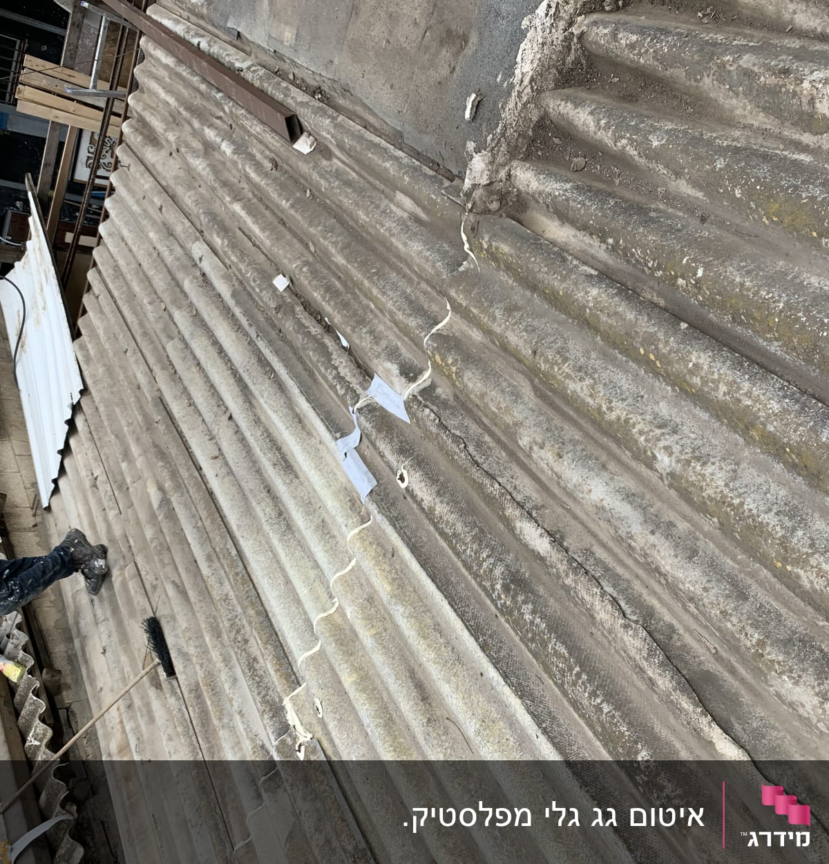 אדם מנקה גג גלי עם מטאטא